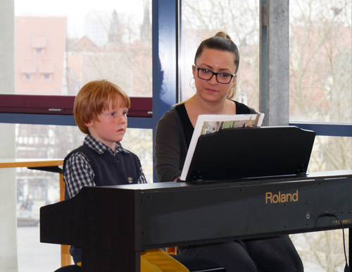 Klavierlehrerin übt mit einem Schüler am Klavier