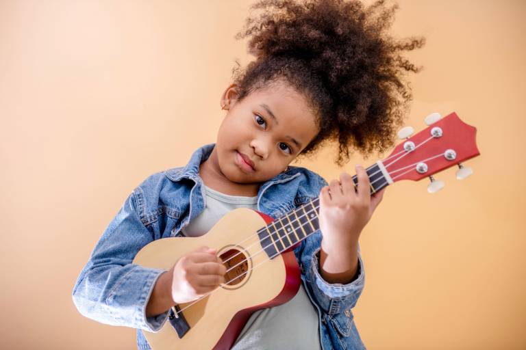 Fröhliches Mädchen spielt Ukulele im Ukulelenunterricht in Erfurt