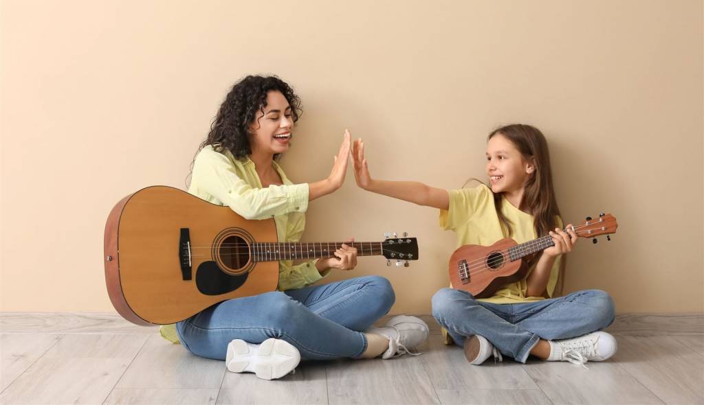 musikunterricht-erfurt-gitarre-ukulele Musiklehrerin mit Gitarre gibt Schülerin mit Ukulele ein High Five