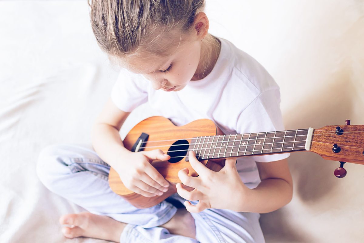 Mädchen legt konzentriert die Finger auf die Ukulele im Musikkurs an der GS am Schwemmbach Erfurt