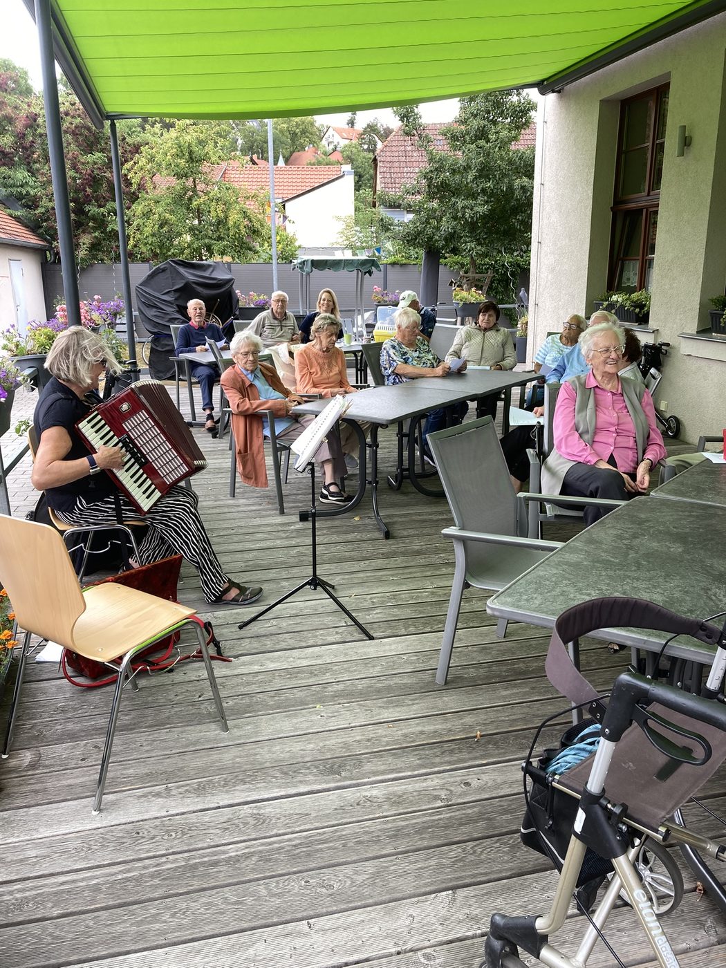 Seniorinnen und Senioren hören beim Sommerkonzert in der Tagespflege Hochheim zu und singen mit
