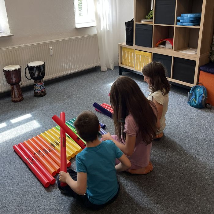 Kinder spielen mit bunten Klangröhren im Unterrichtsraum der Musikschule